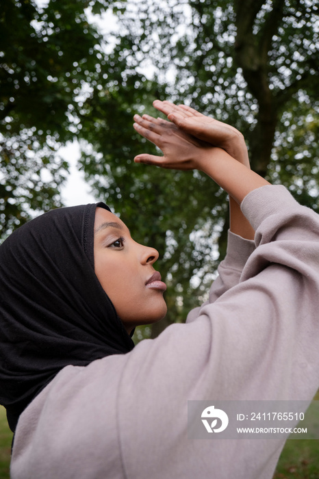 Portrait of woman in hijab practicing yoga in park
