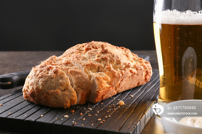 Board with tasty loaf of beer bread on table