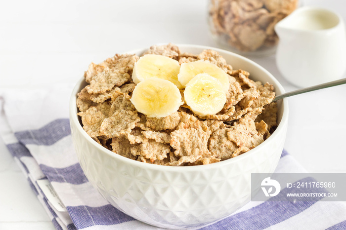 Whole wheat cornflakes with banana slices in white bowl