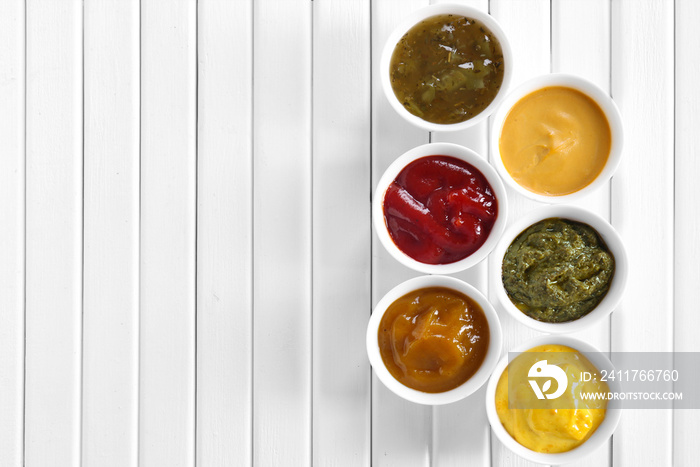 Different tasty sauces in bowls on white wooden table