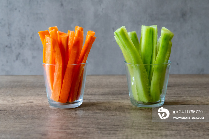 Fresh cucumber and carrots in jars isolated on wood with gray background, copy space, vegan food