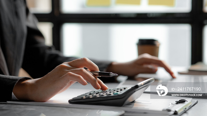 Businessman using a calculator to calculate numbers on a company’s financial documents, he is analyzing historical financial data to plan how to grow the company. Financial concept.