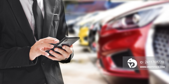 Businessman using smartphone on blurred background of new car displayed in showroom dealer with copy space.