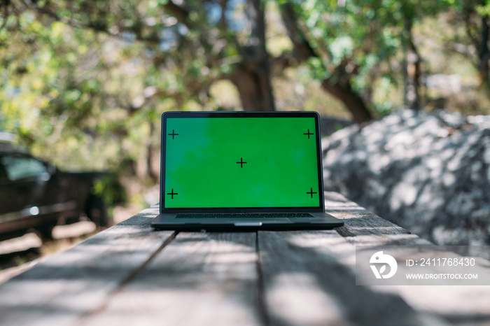 Open laptop on a wooden table in a camping in the mountains