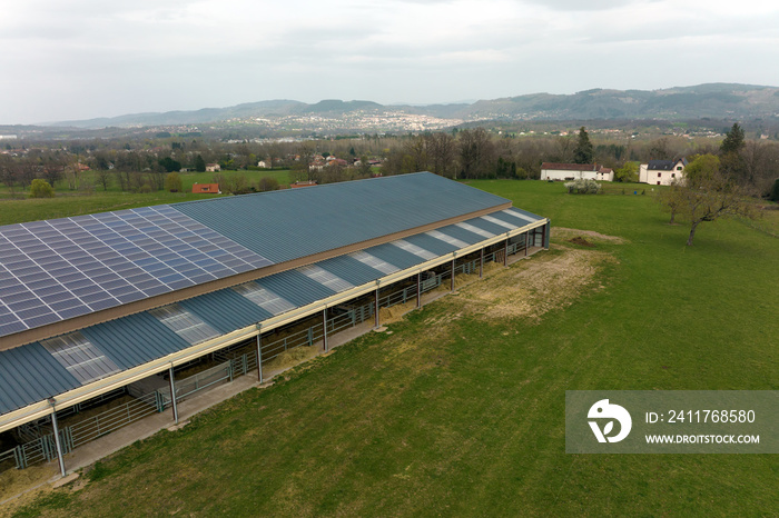 Aerial view of blue photovoltaic solar panels mounted on farm building roof for producing clean ecological electricity. Production of renewable energy concept