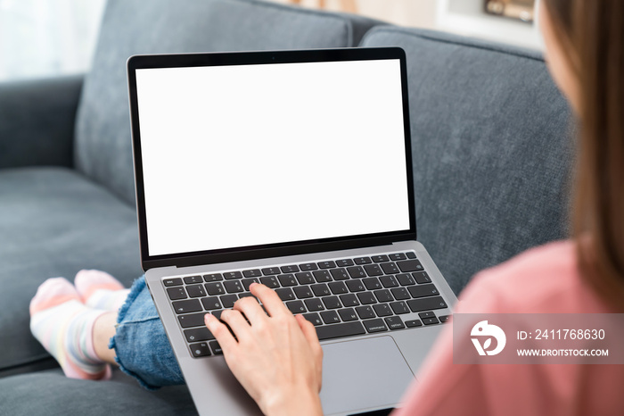 Woman hand using laptop and sitting on the sofa in the house, mock-up of a blank screen for the application.