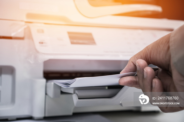 Business Documents concept : Businesswoman hands working in process press of paper in laser printer on busy work desk office. Soft focus