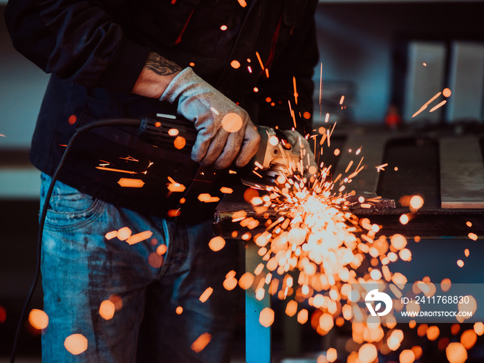 Heavy Industry Engineering Factory Interior with Industrial Worker Using Angle Grinder and Cutting a Metal Tube. Contractor in Safety Uniform and Hard Hat Manufacturing Metal Structures.