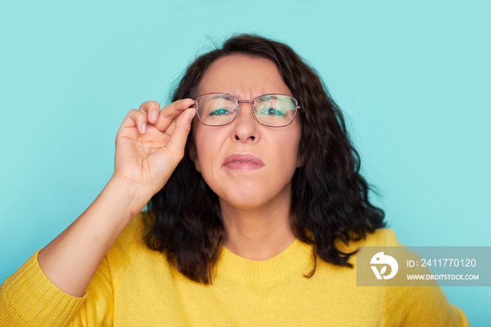 funny shocked face. frames trying eyeglasses. girl holding glasses standing on turquoise background, Concept: poor eyesight.