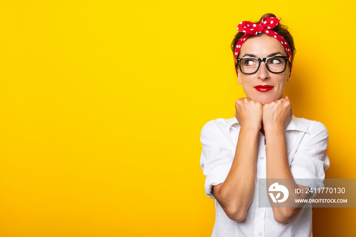 Young woman holds her hands on her chin, wearing glasses and a headband on a yellow background. Banner