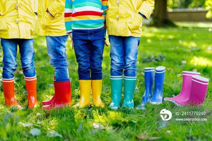 Little kids, boys or girls in jeans and yellow jacket in colorful rain boots