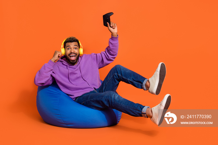 Full length photo of delighted crazy guy raise fist celebrate luck success isolated on orange color background