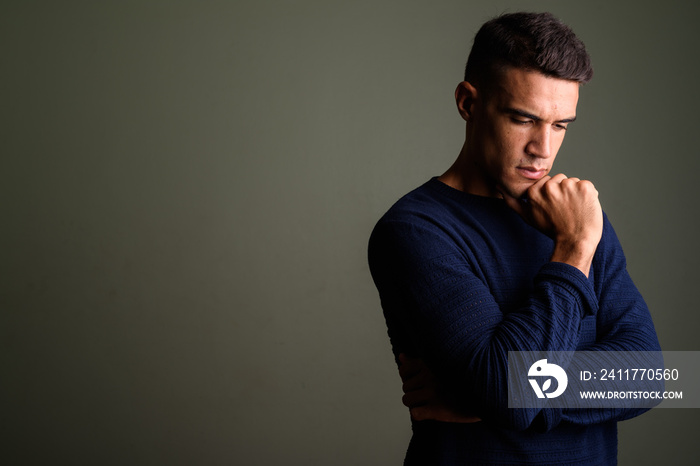 Young handsome man thinking against colored background