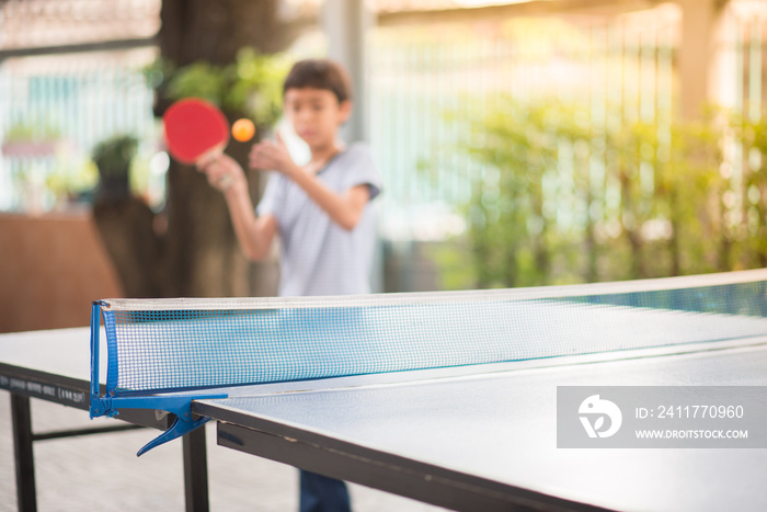 Kid playing table tennis outdoor with family