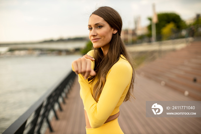 Young woman stretching on the riverside