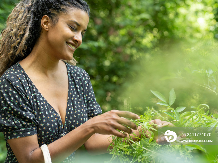 Smiling woman foraging plants into basket