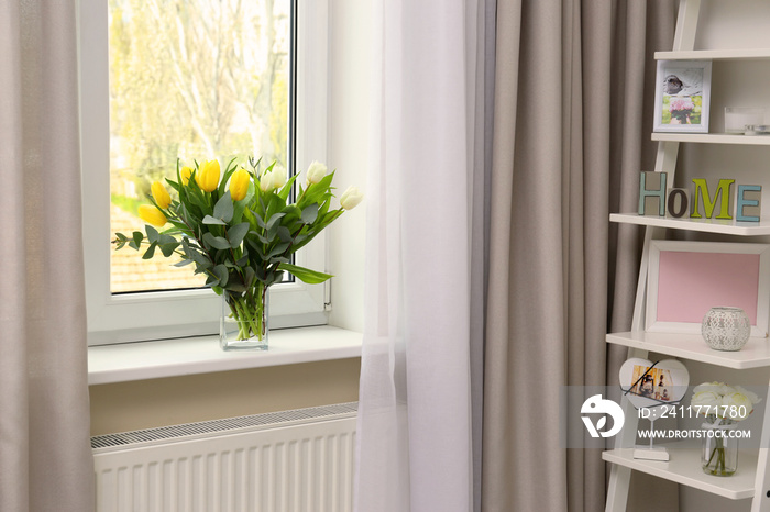 Vase with beautiful tulips on windowsill