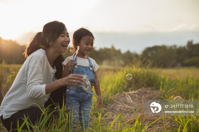 mother and daughter enjoying play with bubble outdoor