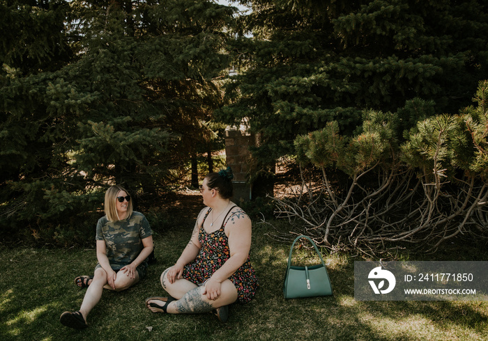 2 friends sit and talk in the park