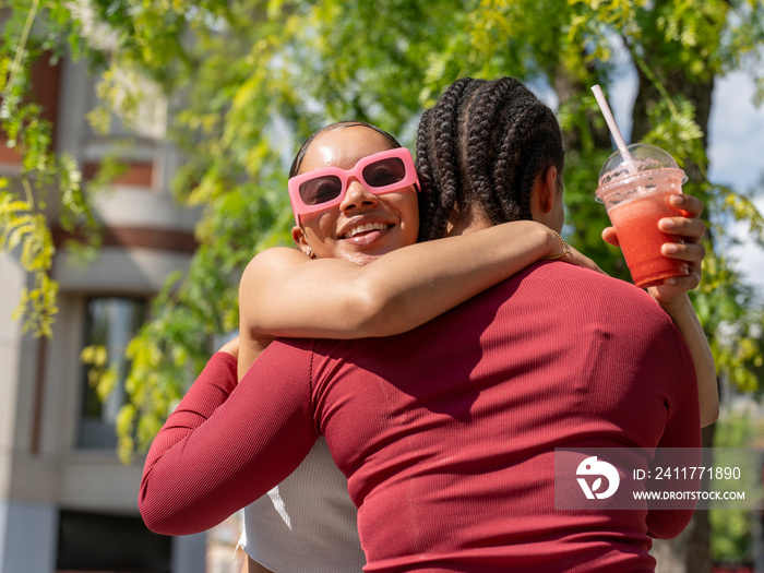 Two female friends embracing on sunny day