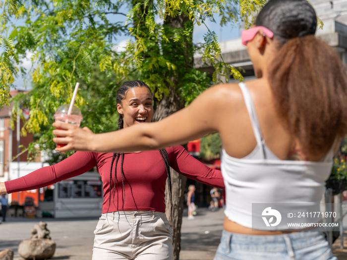 Two female friends greeting in city street