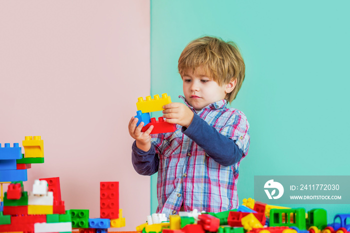 Child playing with colorful toy blocks. Educational toys for young children. Little boy playing with lots of colorful plastic blocks constructor. Boy playing with construction blocks at kindergarten