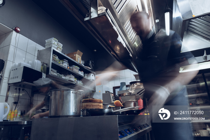 Behind the scenes of brands. The chef cooking in a professional kitchen of a restaurant meal for client or delivery. Open business from the inside. Meals during the quarantine. Hurrying up, motion.