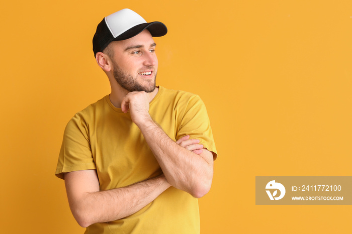 Handsome man in stylish cap on color background