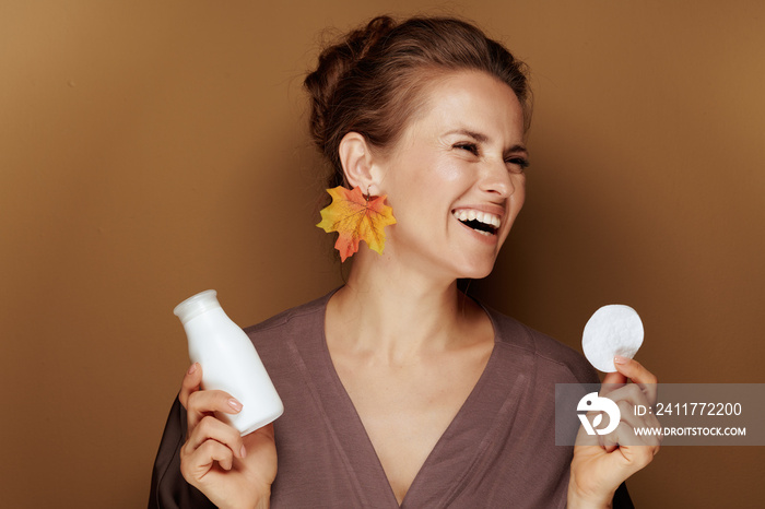 woman with autumn leaf earring holding face cleansing milk