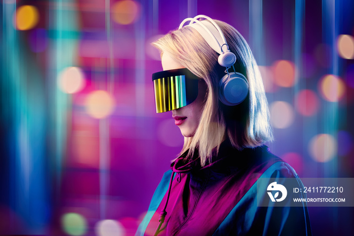 Blonde in VR glasses and headphones on pink background