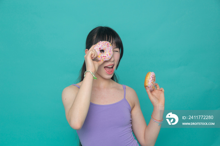 Studio portrait of playful girl holding donuts