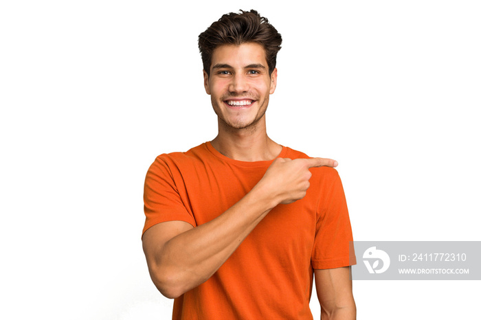 Young caucasian handsome man isolated smiling and pointing aside, showing something at blank space.