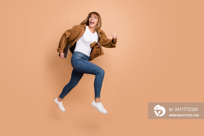 Full size profile side photo of young scared afraid girl running in air hold tablet look copyspace isolated on beige color background