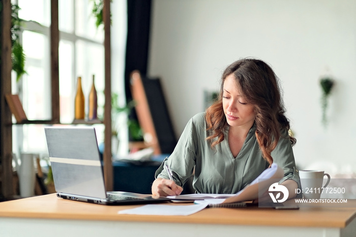 Young woman working from home office. Freelancer using laptop and the Internet. Workplace in living room.