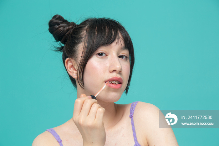 Studio portrait of girl applying lip gloss