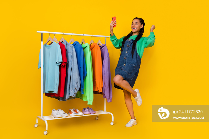 Full length portrait of delighted successful lady use telephone raise fist isolated on yellow color background