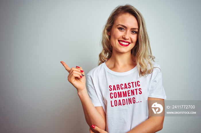 Beautiful woman wearing sacarstic comments loading t-shirt over isolated background with a big smile on face, pointing with hand and finger to the side looking at the camera.