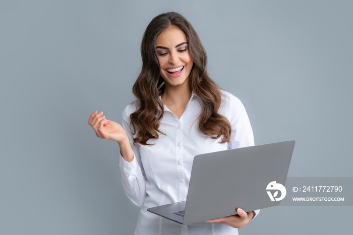 Blogging chatting woman. Pretty assistant holding notebook search information internet. Young business woman with laptop computer isolated studio portrait on gray background. Freelancer at work.