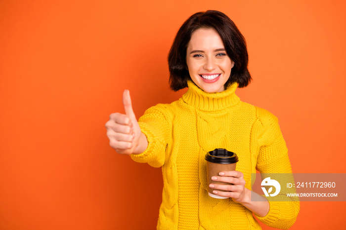 Photo of cheerful nice cute charming pretty sweet girl toothily smiling showing you thumb up sign wearing yellow sweater while isolated with orange background