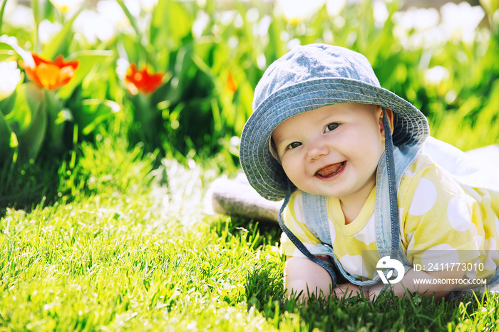 Baby in green grass of tulip field at springtime