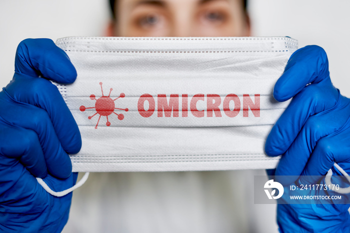 Female doctor holds a face mask with - Omicron variant text on it. Covid-19 new variant - Omicron. Omicron variant of coronavirus. SARS-CoV-2 variant of concern