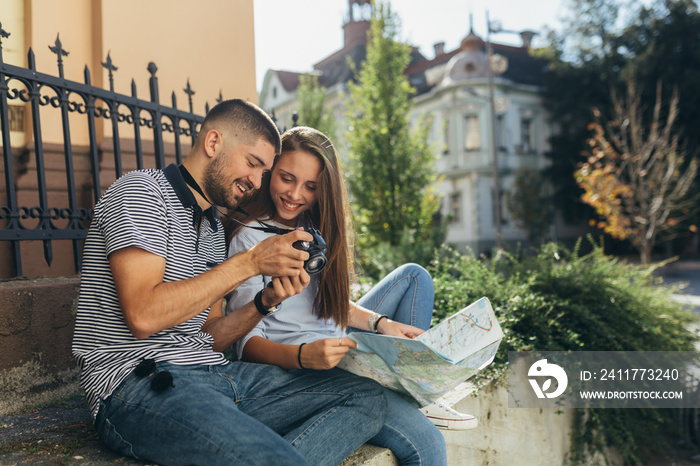 couple tourist in sightseeing in city using paper map and taking picture with camera