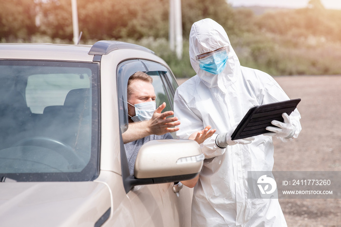 Checking and disinfecting car for virus COVID-19 and bubonic plague border of city and country. Doctor in biohazard suit informs driver of danger