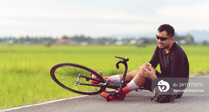 Bike injuries. Man cyclist fell fell off road bike while cycling. Bicycle accident, injured knee. Road in Thailand.