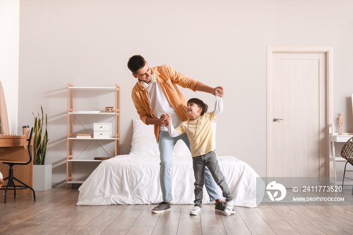 Man and his little son dancing in bedroom