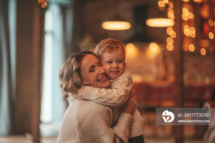 Candid authentic happy mom spends time with her cheerful child at wooden lodge Xmas decorated