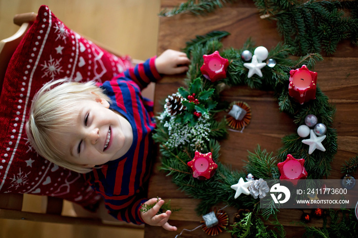 Little cute blonde toddler boy, making advent wreath at home