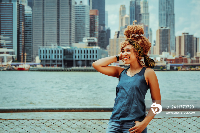 Portrait beautiful young adult woman afro hairstyle with Manhattan New York City skyline in the background outdoors shot