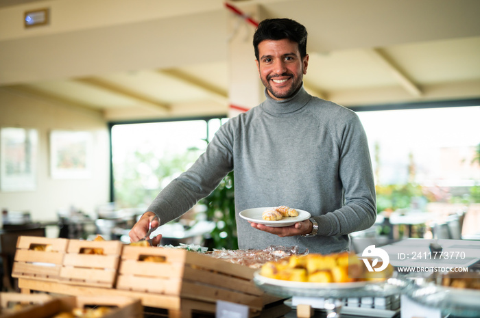 Man picking food at a buffet in a hotel for his breakfast