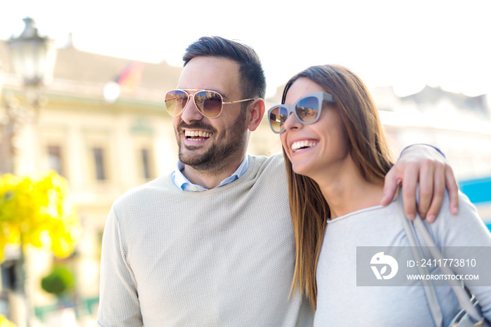 Beautiful young couple smiling while walking outdoors on sunny day